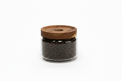 A clear glass jar filled with dark brown peppercorns, topped with a round wooden lid, shown on a white background with dimension lines indicating 90 mm width and 80 mm height.